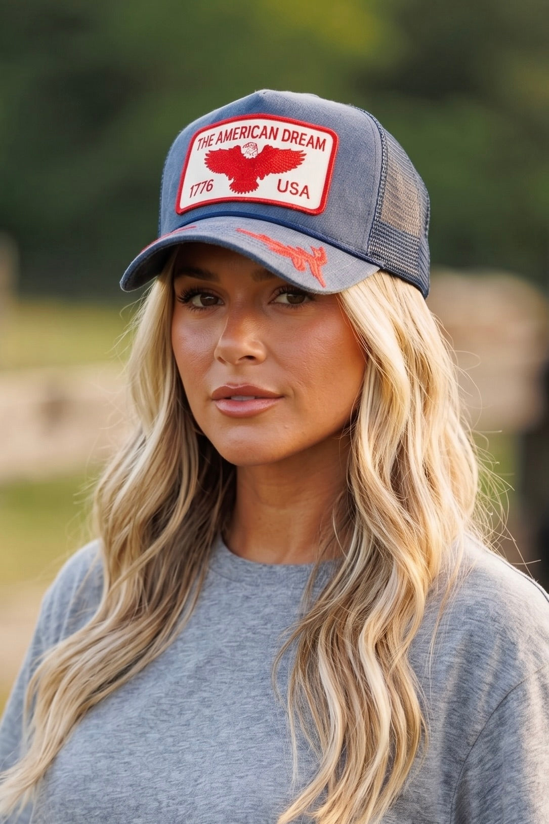 Vintage blue suede trucker hat featuring a red embroidered "The American Dream 1776 USA" eagle patch, red embroidered brim details, mesh back, and adjustable snapback closure.