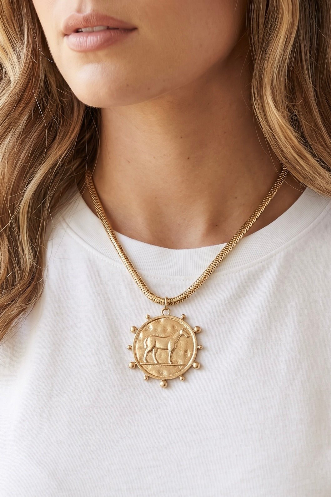 Gold tone western horse medallion necklace with round raised horse pendant and snake-style chain.
