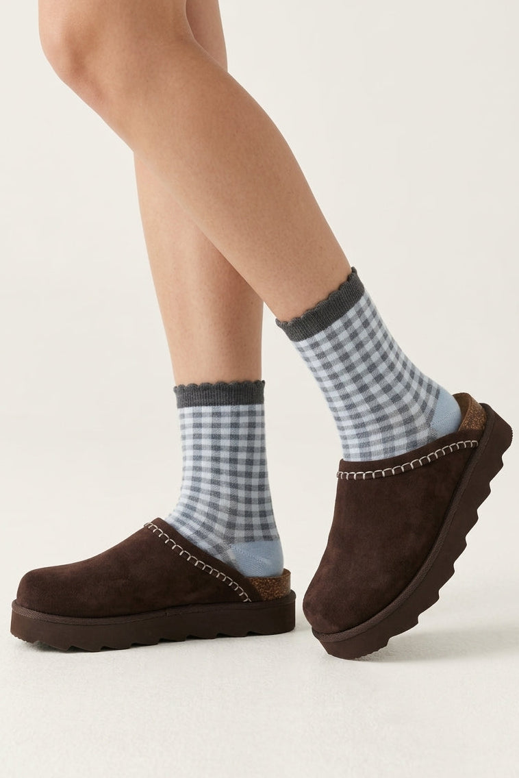 Brown suede platform clogs with contrast stitching, cork heel detail, and chunky lug soles styled with blue gingham socks.