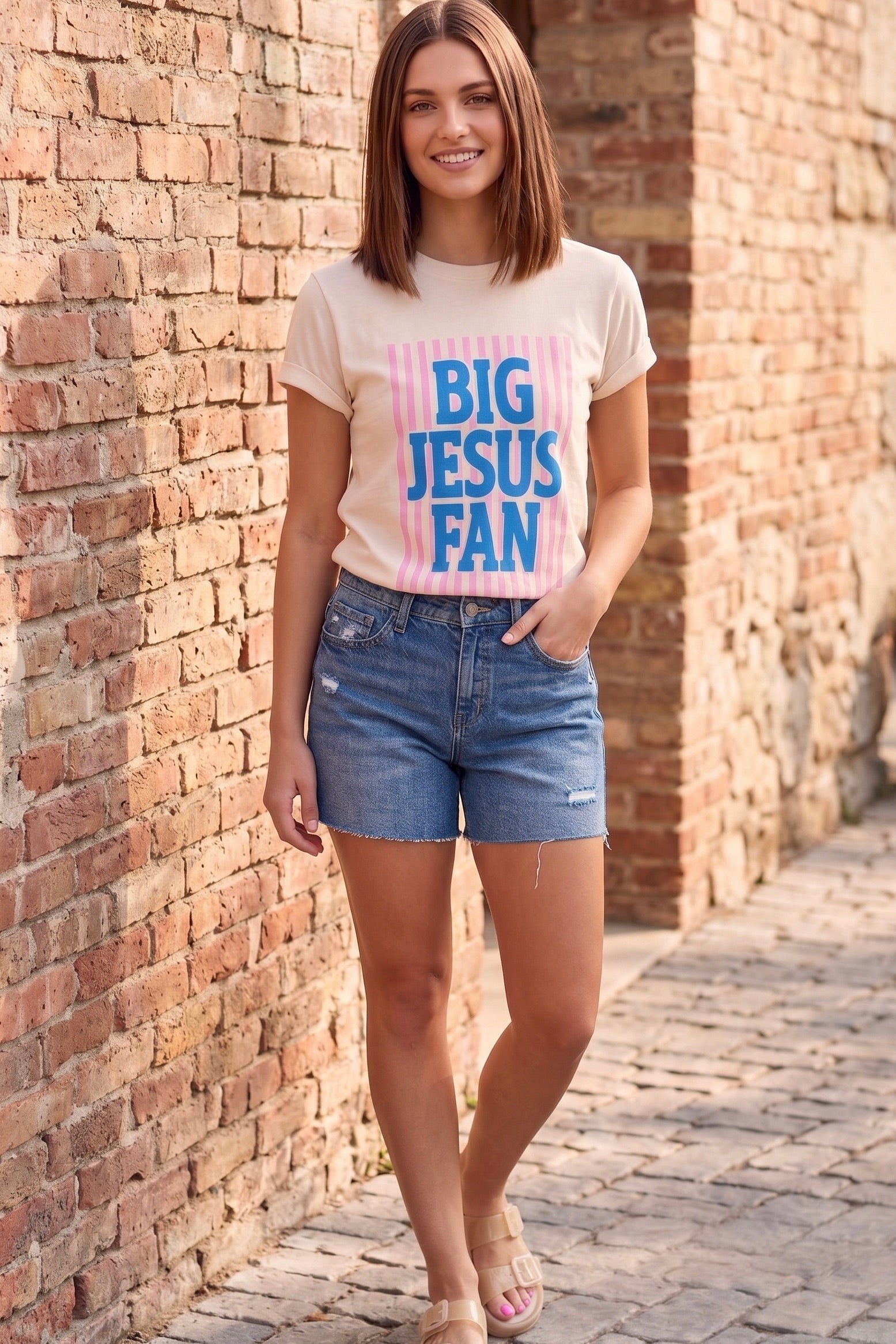 Cream graphic tee featuring a colorful Big Jesus Fan design styled with a leopard midi skirt and western boots for a faith-inspired boutique outfit.
