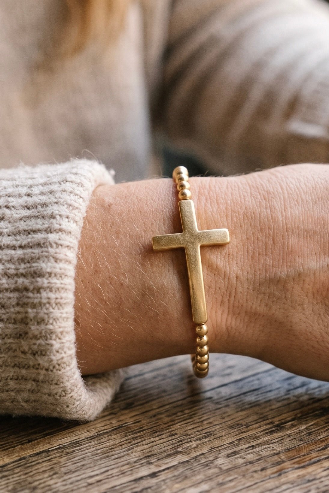 Women’s worn gold-tone cross stretch bracelet featuring round gold ball beads and a large minimalist 1.75-inch cross centerpiece, designed as everyday faith-inspired jewelry.