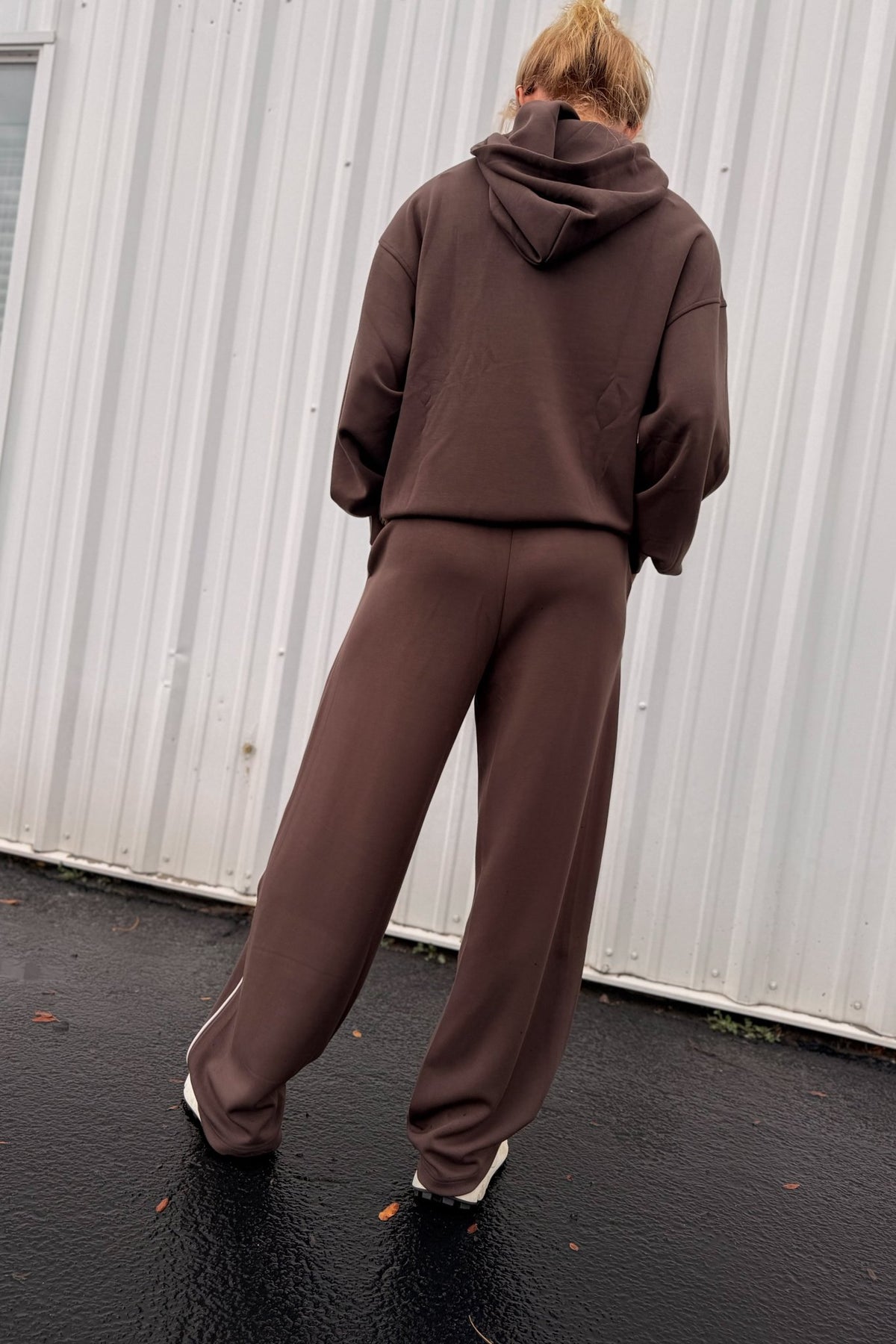 Women’s chocolate brown pullover hoodie featuring a relaxed oversized fit, drawstring hood, dropped shoulders, long sleeves, front kangaroo pocket, and contrast ivory piping detail along the pocket and sides. Coordinating chocolate brown wide-leg sweatpants are available separately for a matching lounge set.
