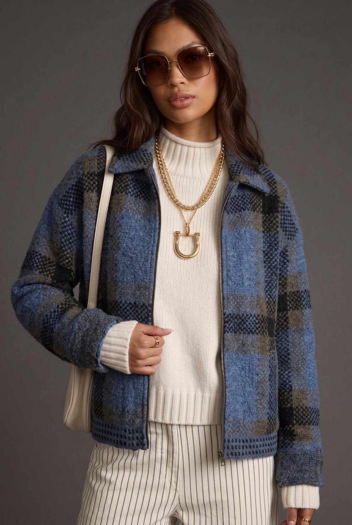 Women's dusty blue, charcoal gray, and brown plaid knit sweater jacket featuring a soft, textured brushed knit fabric, oversized buffalo check-inspired plaid pattern, relaxed boxy silhouette, classic fold-over collar, full front zipper closure, dropped shoulders, and long sleeves. This cozy, hip-length zip-up cardigan jacket features contrasting textured knit details along the hem and cuffs, combining vintage-inspired plaid styling with modern casual outerwear. Perfect for fall layering, winter outfits, coz