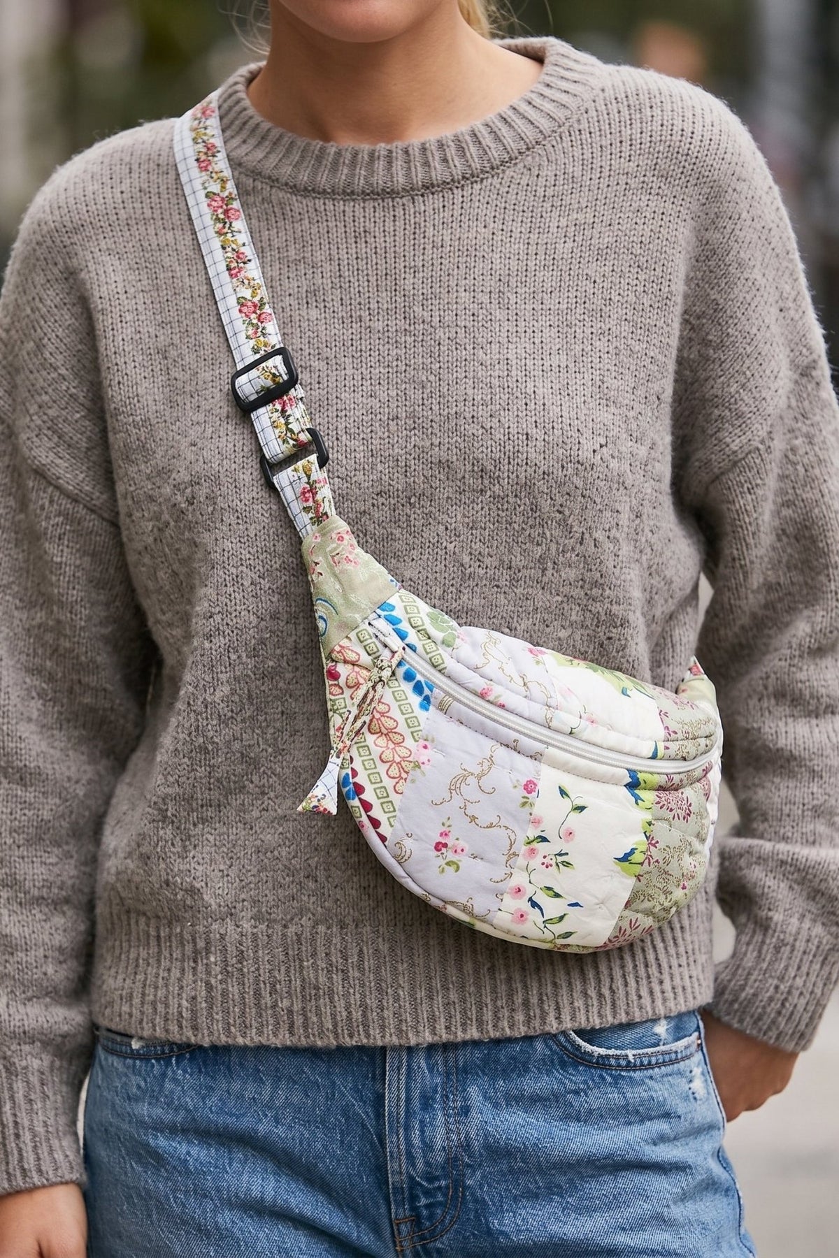 Vintage-inspired quilted patchwork crescent crossbody bag with mixed floral prints, curved silhouette and adjustable fabric strap.