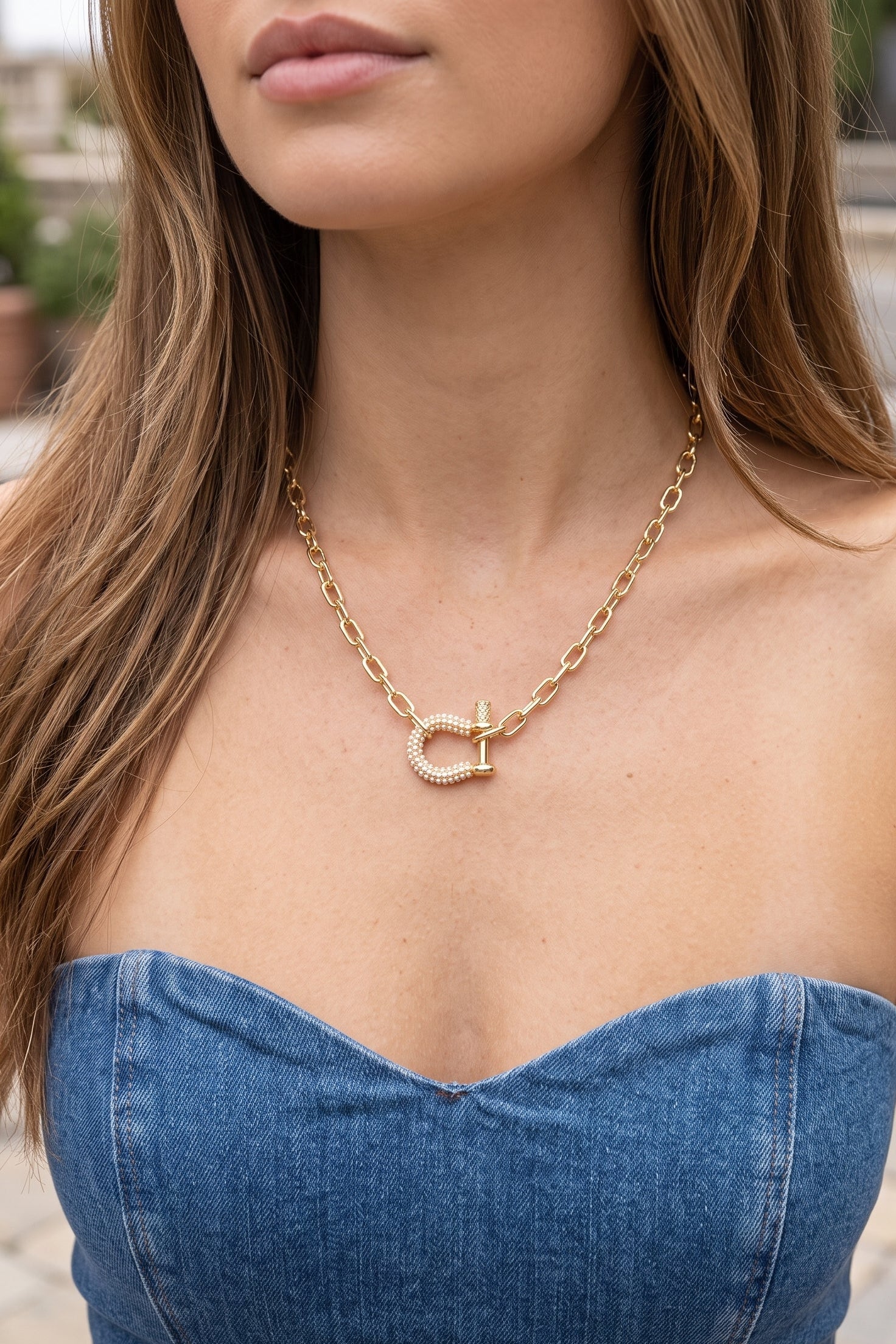 Luck Be A Lady Pearl Horseshoe Necklace featuring a shiny gold elongated link chain and pearl-accented horseshoe toggle centerpiece.