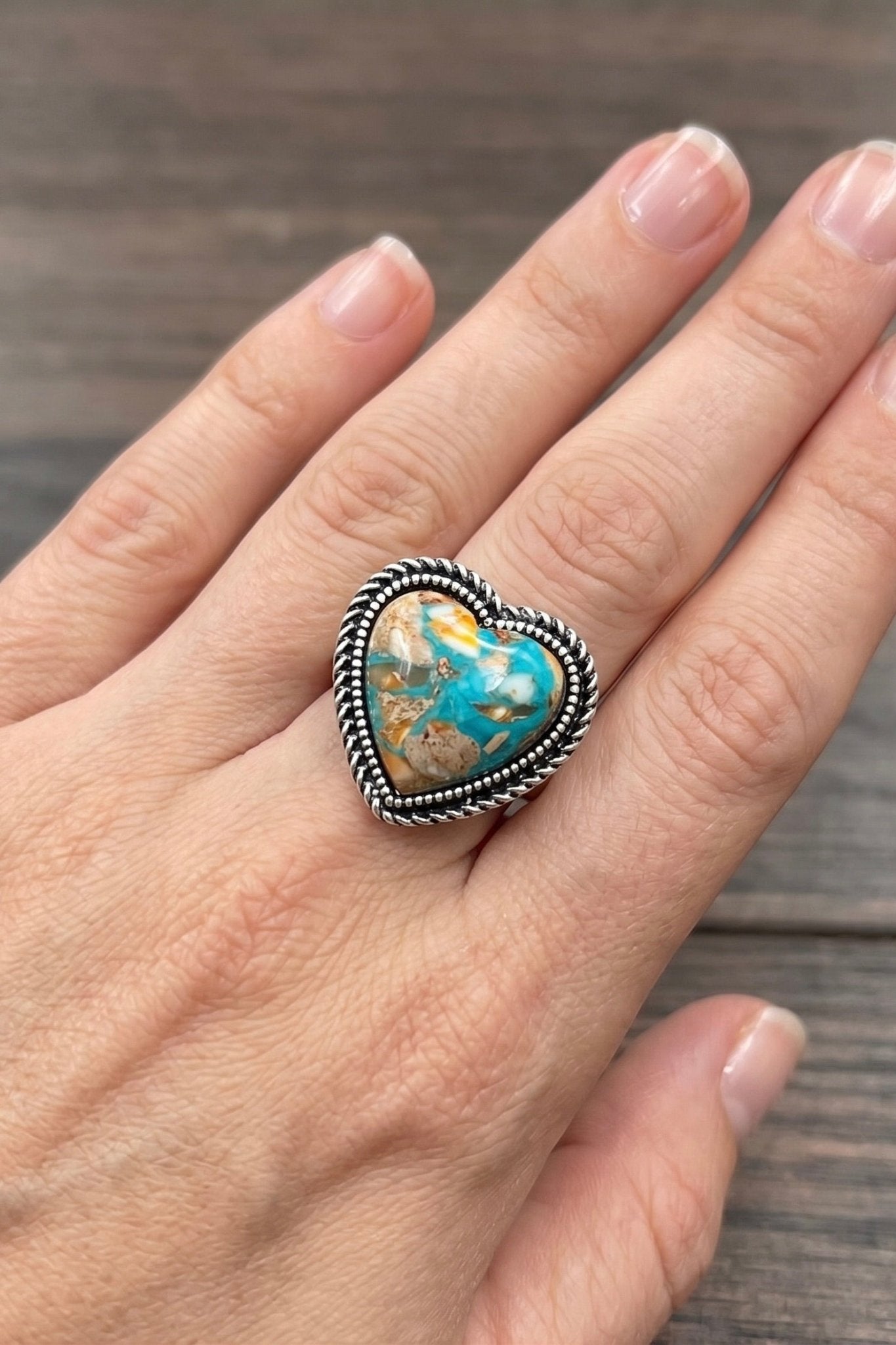 Heart-shaped turquoise gemstone statement ring with antique silver western detailing and adjustable band, perfect for boho cowgirl and Southwestern-inspired outfits.