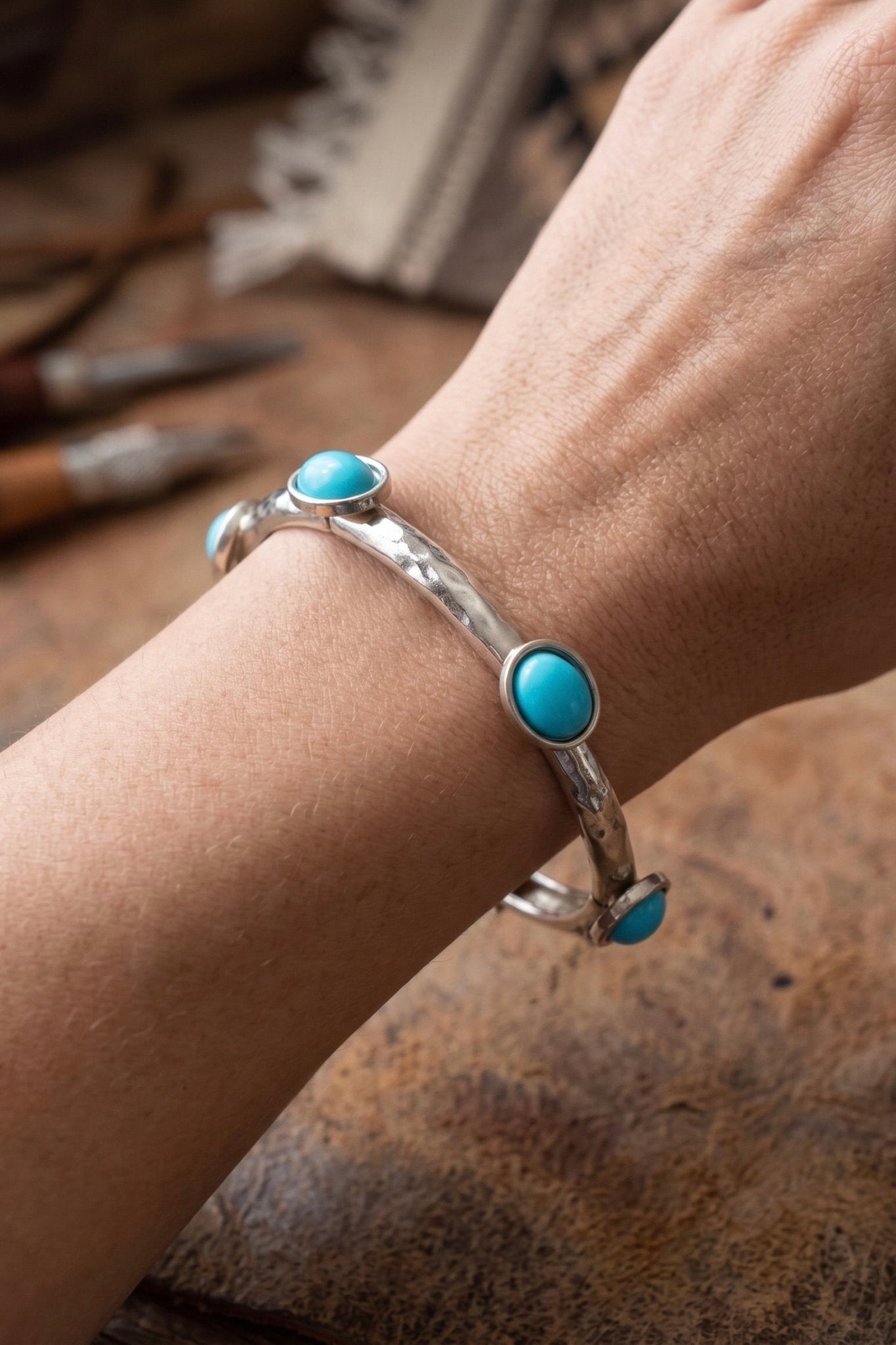 Silver stretch bracelet with turquoise stones and organic metal detailing in a western-inspired bangle design.