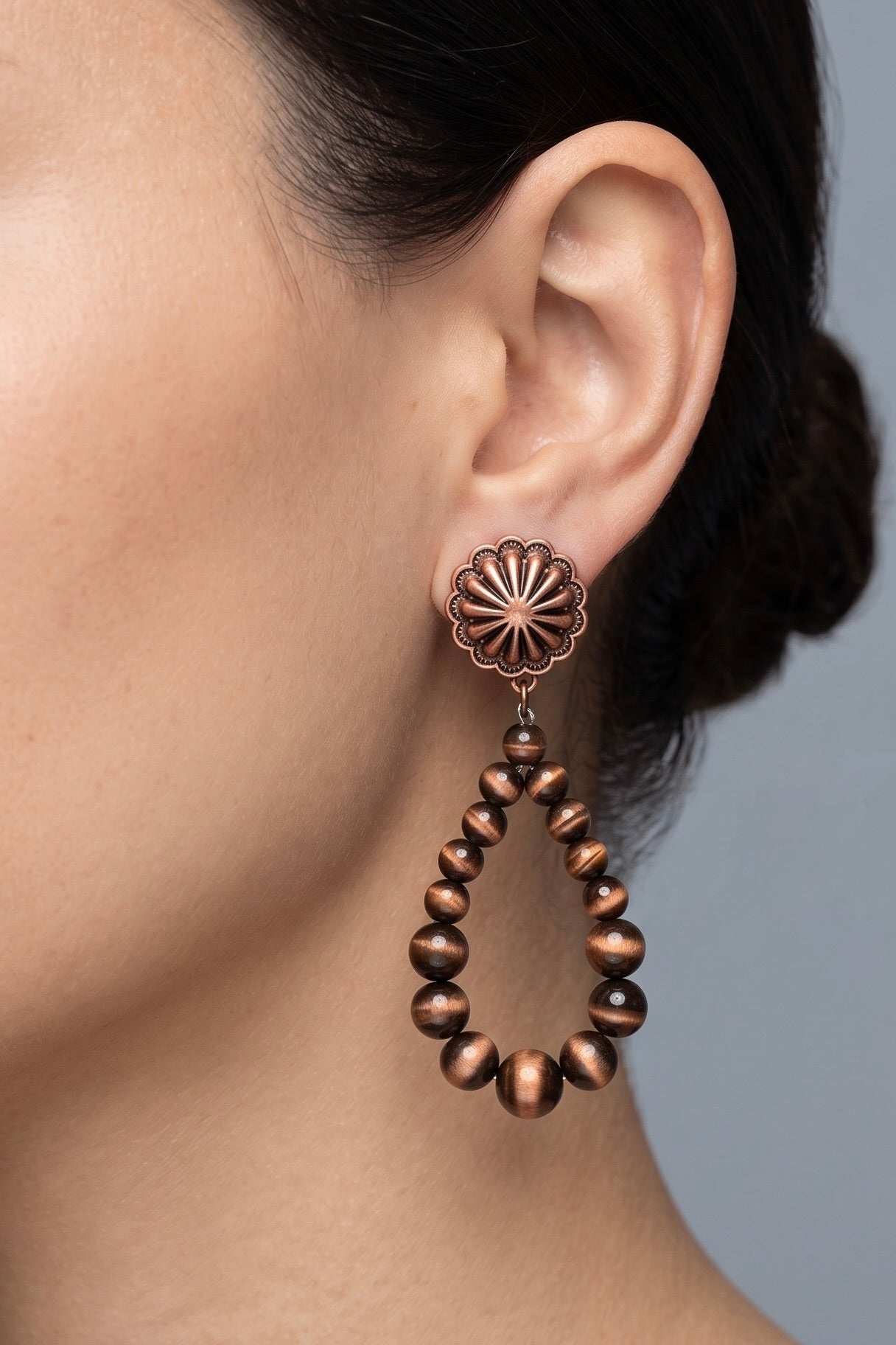 Antique copper-tone teardrop earrings with graduated Navajo-style beads and round floral brass concho post tops.