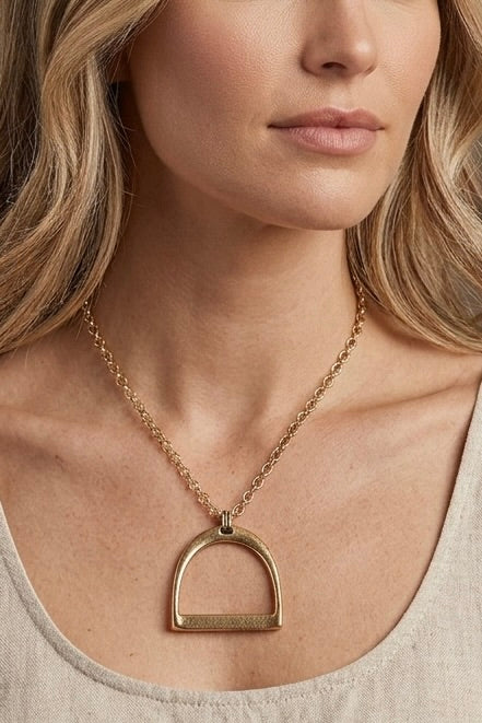 Gold western stirrup pendant necklace on an adjustable chain featuring a minimalist equestrian-inspired design.