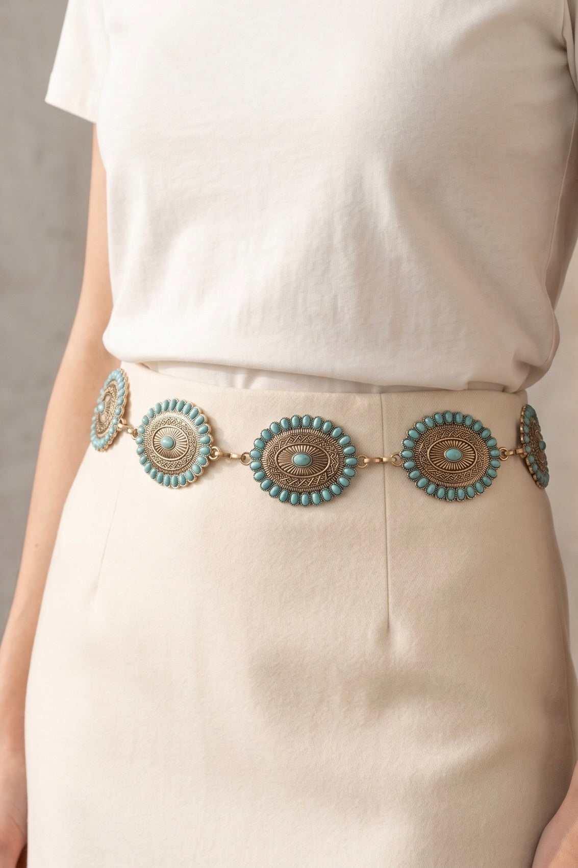 Western chain belt with antique gold oval conchos featuring turquoise stud accents, styled around a white skirt for a classic cowgirl-inspired look.