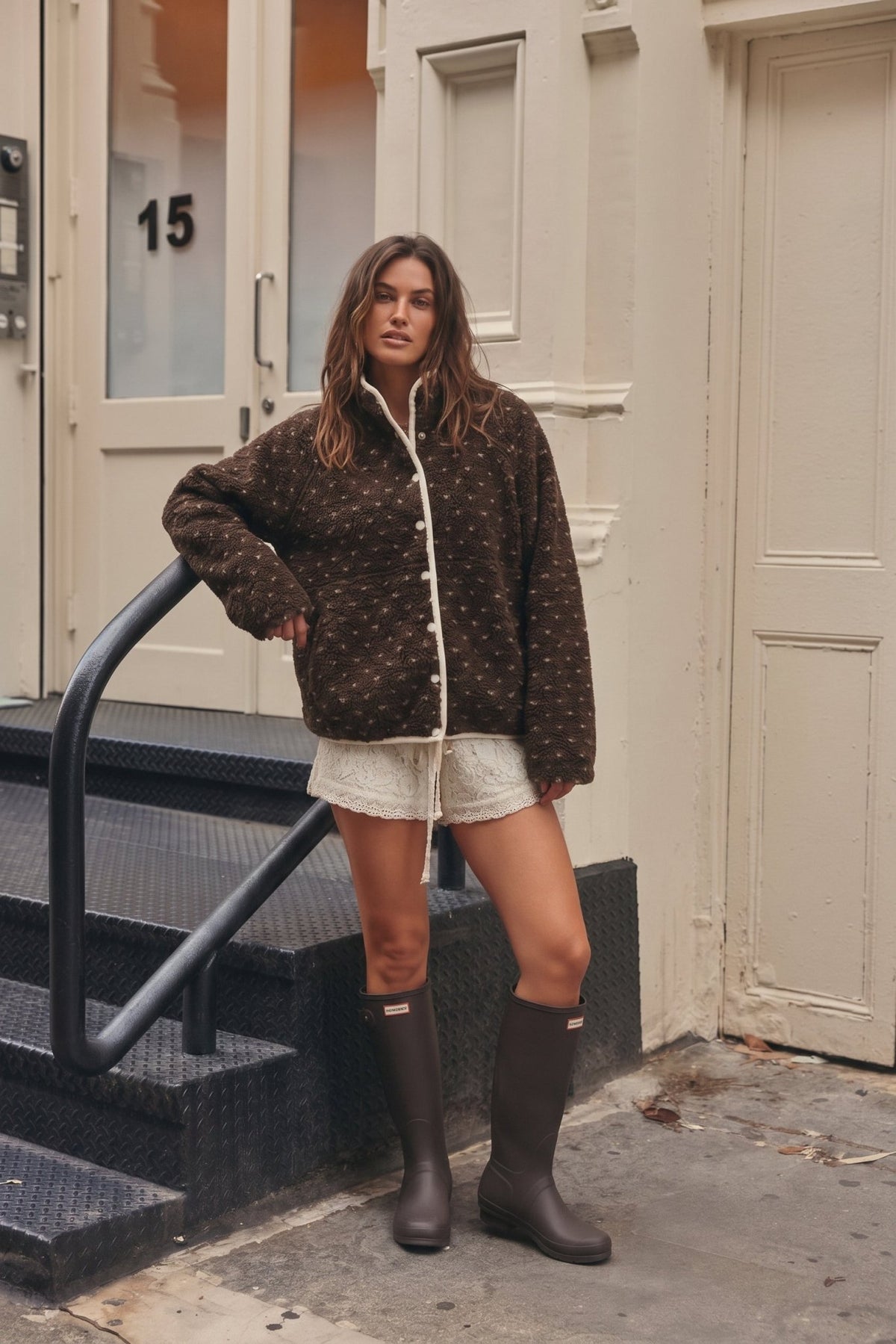 Women's chocolate brown sherpa fleece jacket featuring an ultra-plush, fuzzy teddy bear texture with an allover scattered ivory speckled dot pattern. Designed with a cozy high mock neckline, contrasting cream trim along the front opening and collar, white snap-button front closure, relaxed oversized silhouette, dropped shoulders, This soft, textured sherpa jacket features a slightly cropped, boxy fit with a rounded hem, combining vintage-inspired