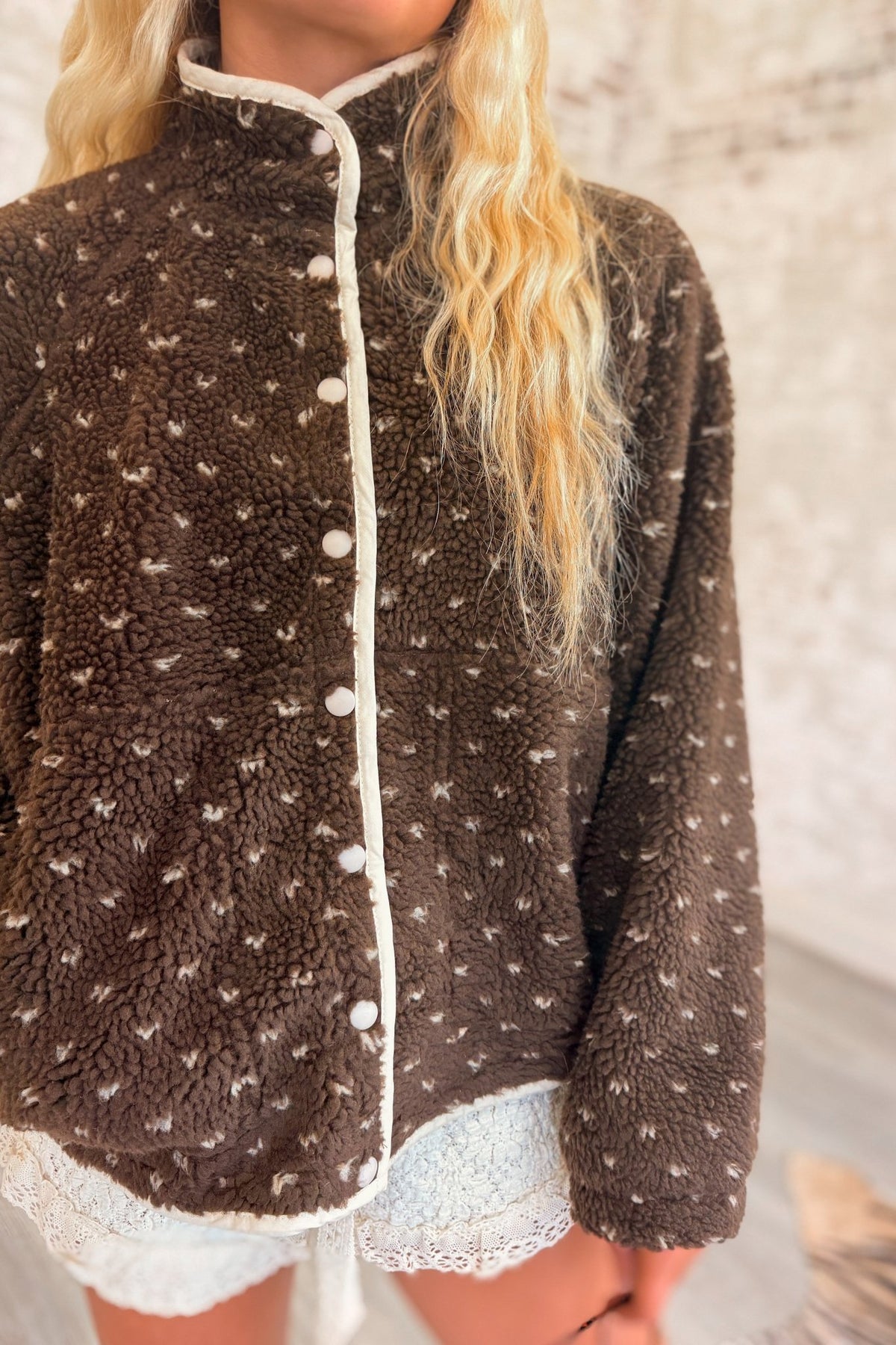 Women's chocolate brown sherpa fleece jacket featuring an ultra-plush, fuzzy teddy bear texture with an allover scattered ivory speckled dot pattern. Designed with a cozy high mock neckline, contrasting cream trim along the front opening and collar, white snap-button front closure, relaxed oversized silhouette, dropped shoulders, This soft, textured sherpa jacket features a slightly cropped, boxy fit with a rounded hem, combining vintage-inspired