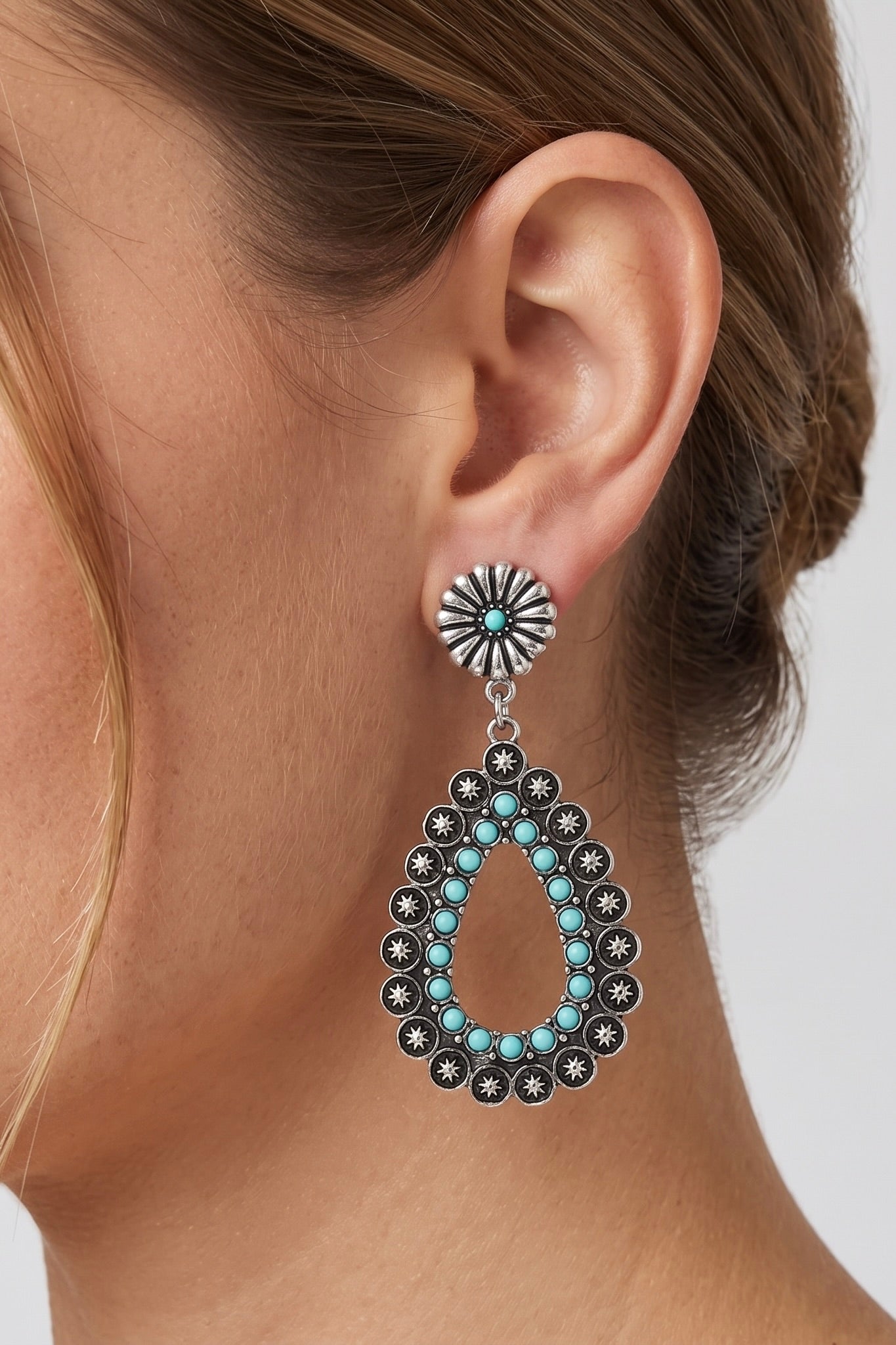 Antique silver Western concho teardrop post earrings featuring turquoise-inspired accents and starburst details in a lightweight statement design.