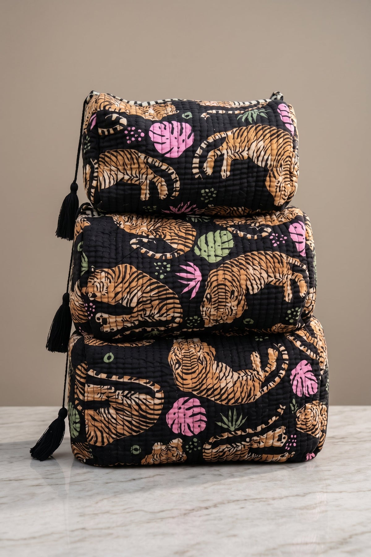 Black Roam If You Want To quilted tiger makeup bag set in three sizes with colorful tropical accents and black tassel zipper pulls.