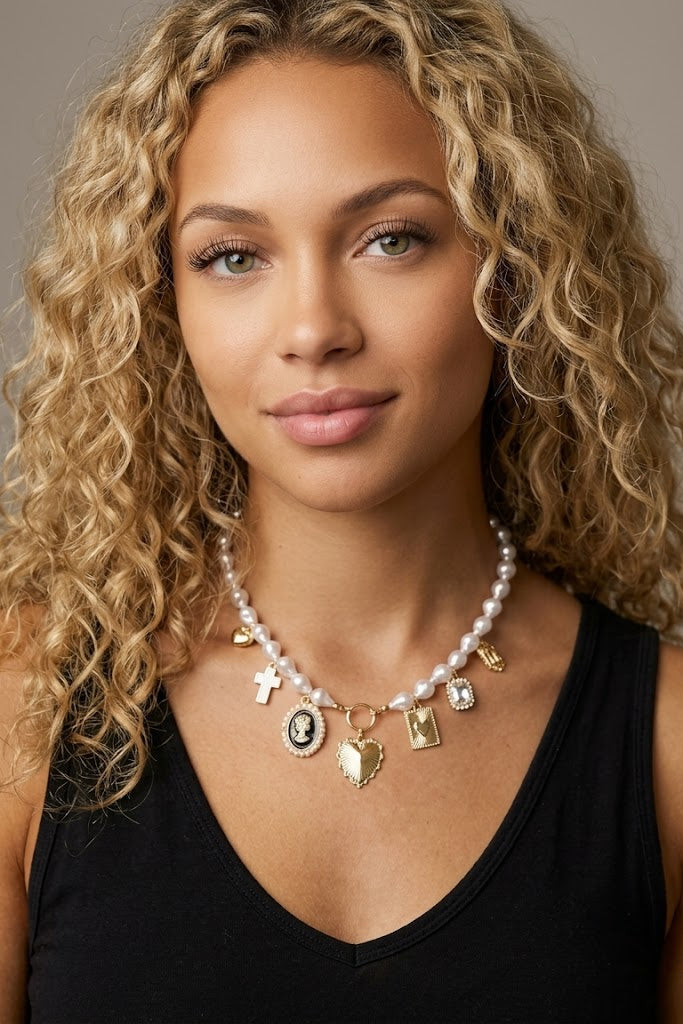 Vintage-inspired pearl charm necklace featuring heart, cross, cameo, and crystal charms on a delicate pearl chain, styled for romantic heirloom jewelry and feminine everyday fashion.