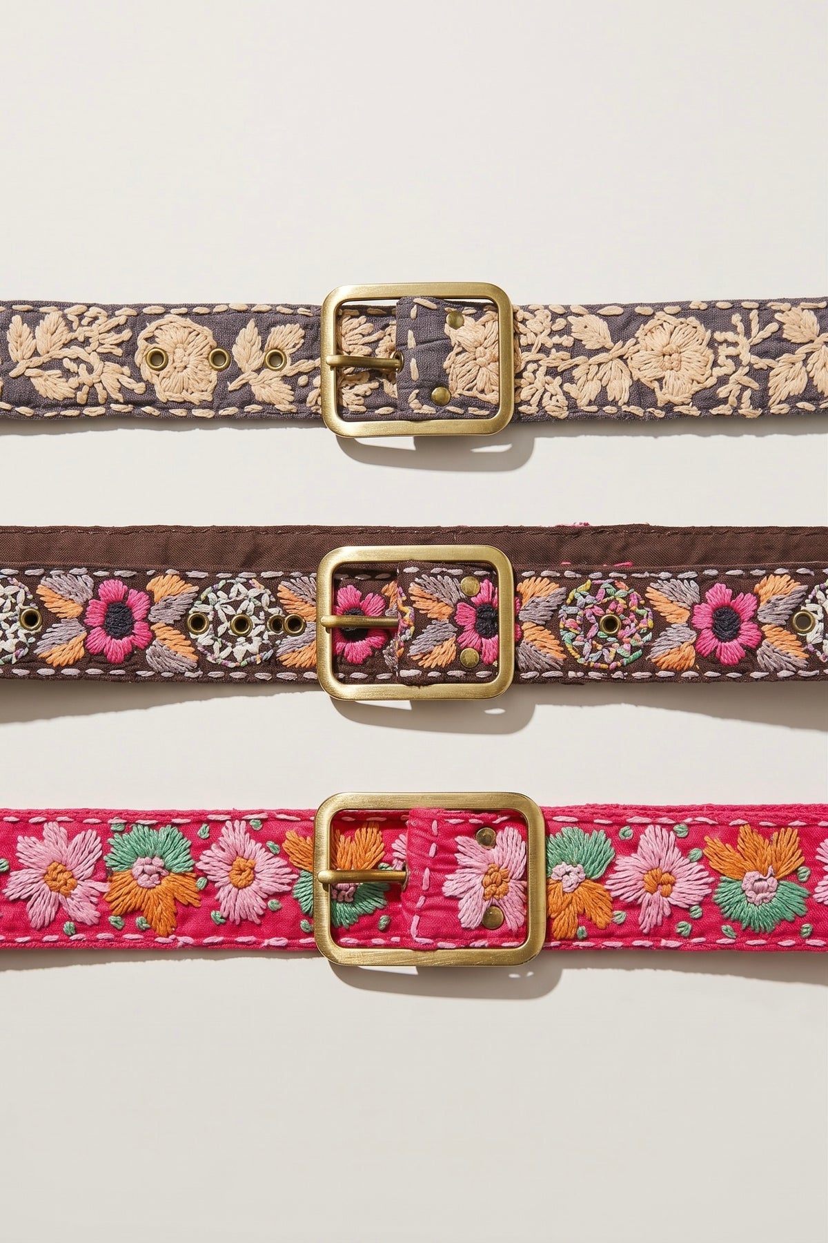 Brown embroidered fabric belt with pink, orange, grey and ivory stitched details and antique gold-tone metal buckle.