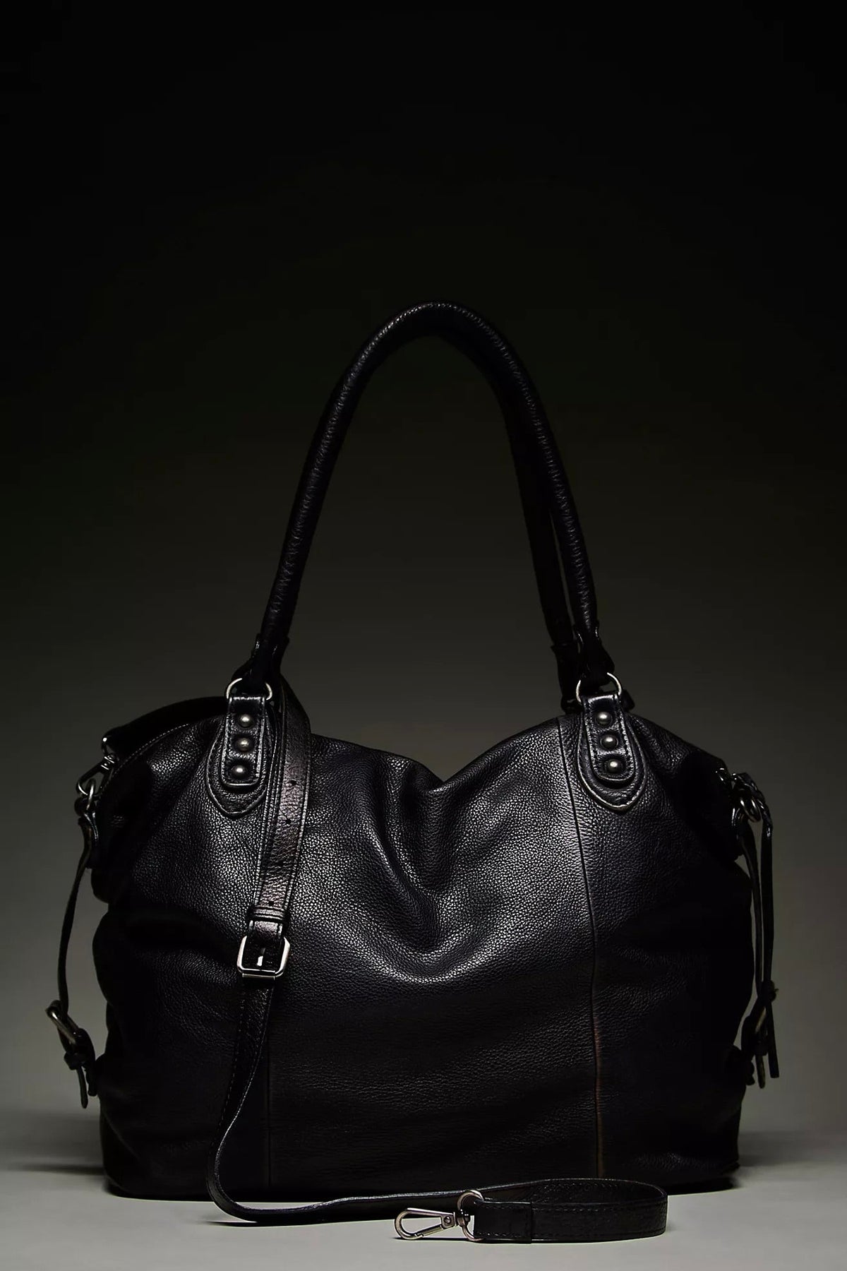 We The Free by Free People Emerson Tote Bag, a slouchy washed leather women’s carryall featuring a spacious interior, exterior zipper compartments, multiple pockets, buckle details, two top handles, adjustable detachable shoulder strap and zipper closure, available in Black, Saddle and Rusty Red.