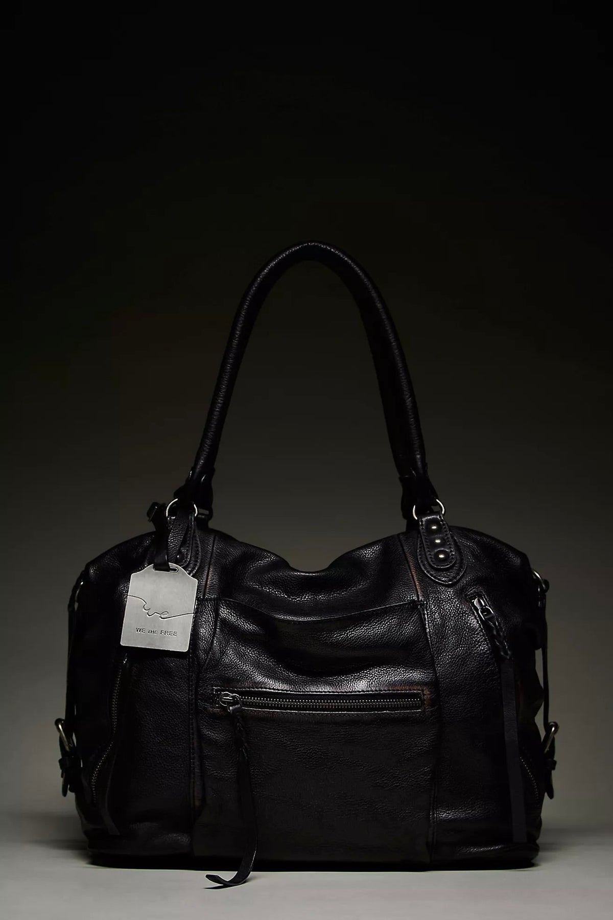 We The Free by Free People Emerson Tote Bag, a slouchy washed leather women’s carryall featuring a spacious interior, exterior zipper compartments, multiple pockets, buckle details, two top handles, adjustable detachable shoulder strap and zipper closure, available in Black, Saddle and Rusty Red.