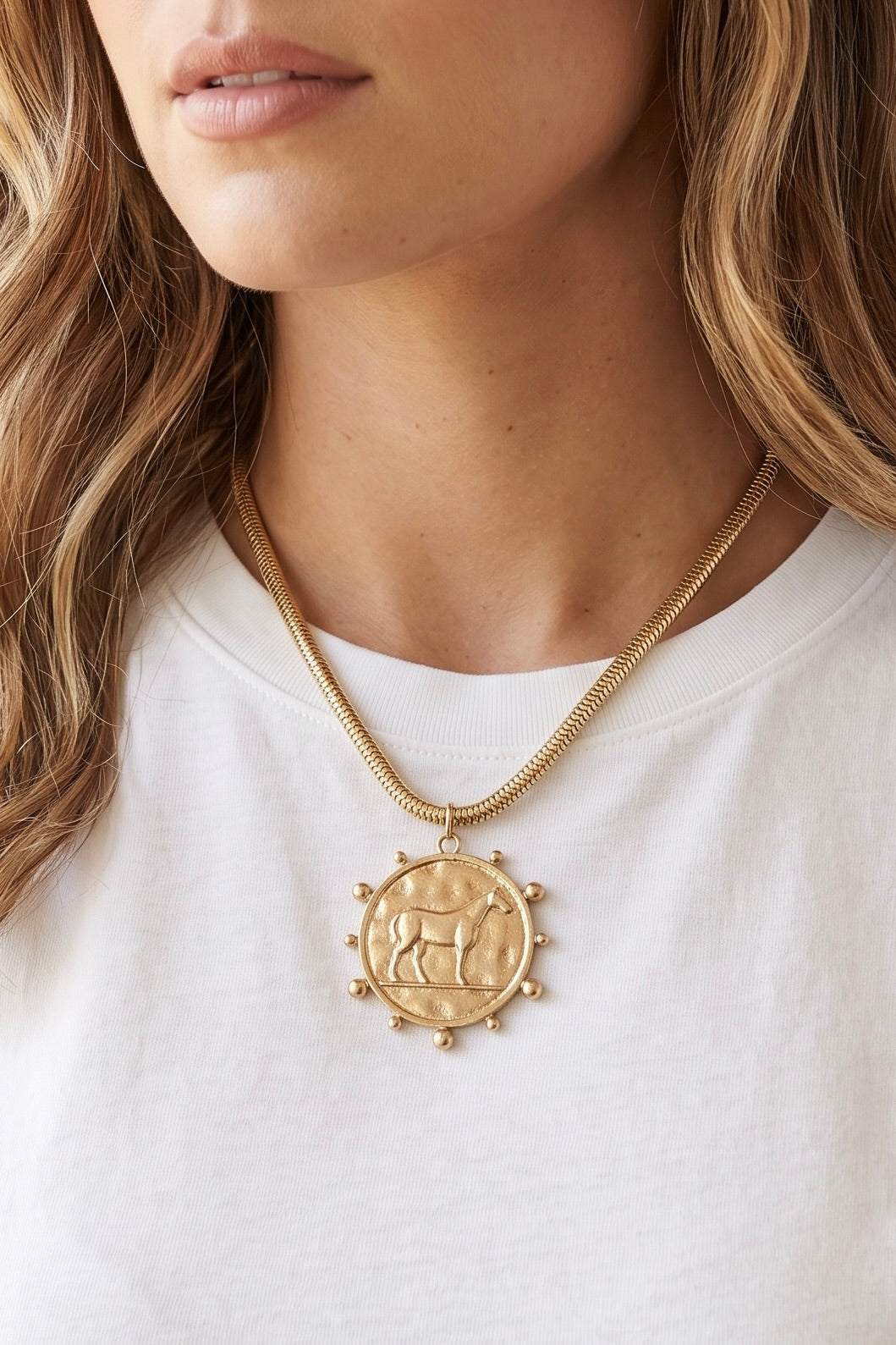 Gold tone western horse medallion necklace with round raised horse pendant and snake-style chain.