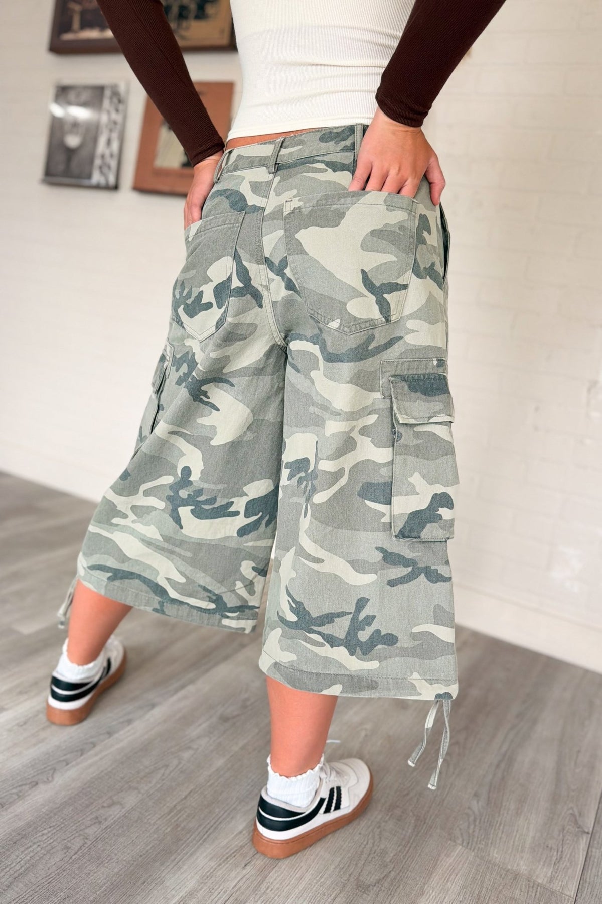 Women’s washed gray and sage camouflage cargo culotte jorts with a low-rise waist, oversized wide-leg below-the-knee silhouette, side flap utility pockets and adjustable drawstring hems.