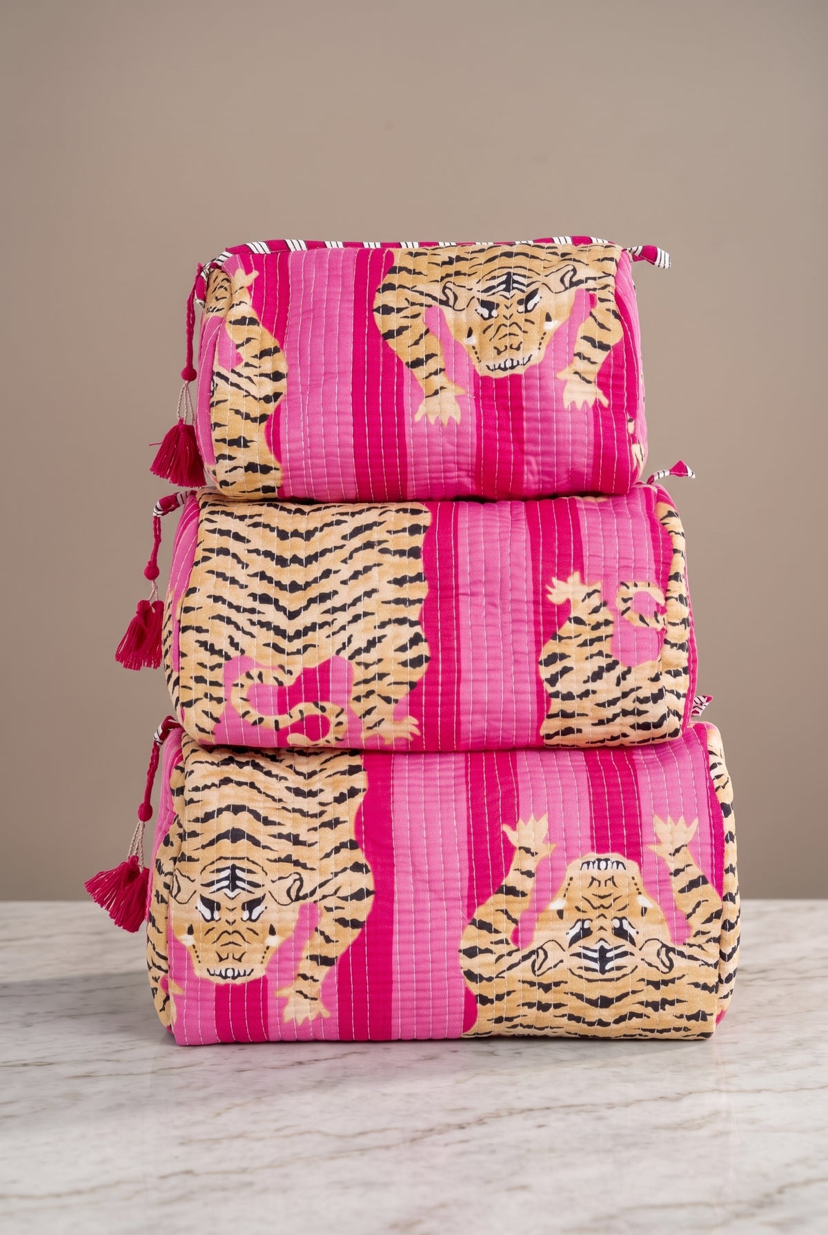 Pink Roam If You Want To quilted tiger makeup bag set in three sizes with bold tiger print, tonal pink stripes, and tassel zipper pulls.