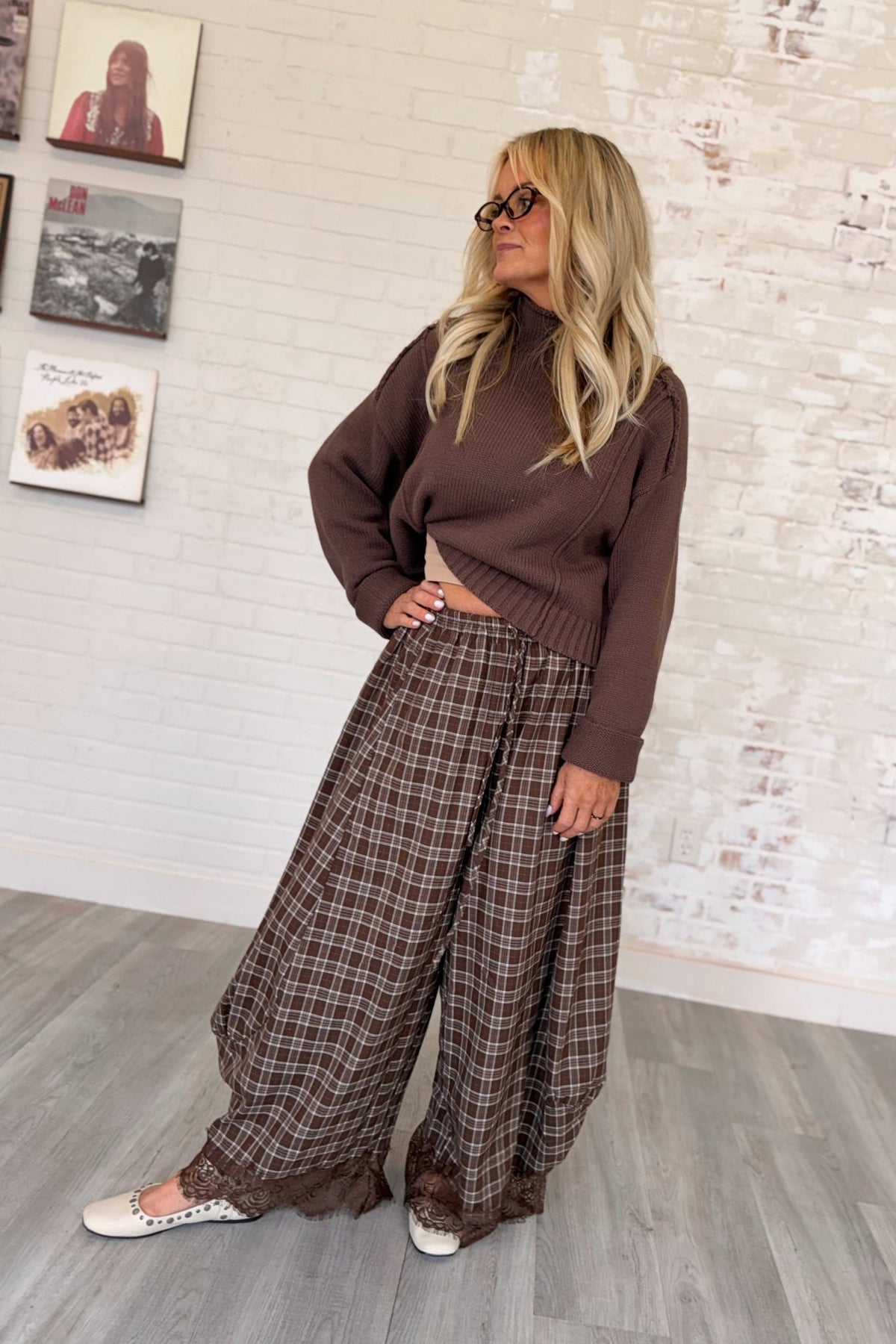 Women's brown and tan plaid wide-leg barrel pants featuring a relaxed, flowy silhouette, lightweight woven fabric, elastic waistband with adjustable drawstring, side pockets, and intricate chocolate brown floral lace trim along the hems. These boho-inspired, full-length plaid pants combine vintage romantic styling with a modern oversized fit, perfect for fall outfits, casual layering, and bohemian boutique fashion.