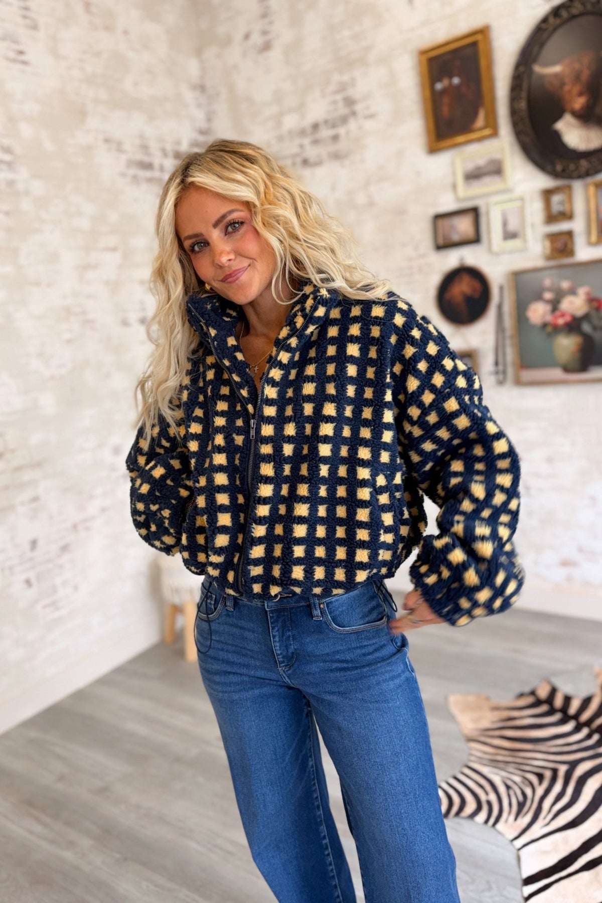 Women's navy blue and buttery yellow checkered sherpa fleece zip-up jacket featuring an allover gingham-inspired square pattern, plush textured teddy fabric, oversized relaxed silhouette, high stand collar, full front zipper closure, long voluminous sleeves with gathered elastic cuffs, and an adjustable drawstring hem for a customizable fit. This cozy, cropped-style sherpa jacket combines retro checkerboard styling with a playful, sporty aesthetic, perfect for casual fall outfits, winter layering, everyday 