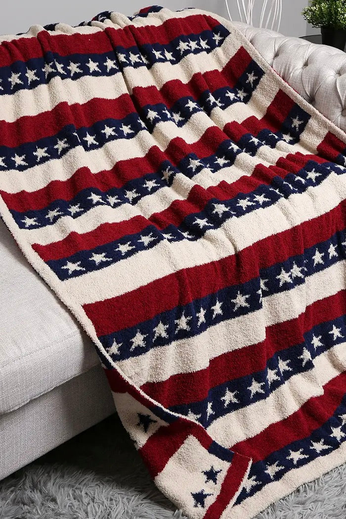 Reversible American flag throw blanket with red, white, and navy stripes and star patterns, featuring two coordinating patriotic designs and a soft plush texture.