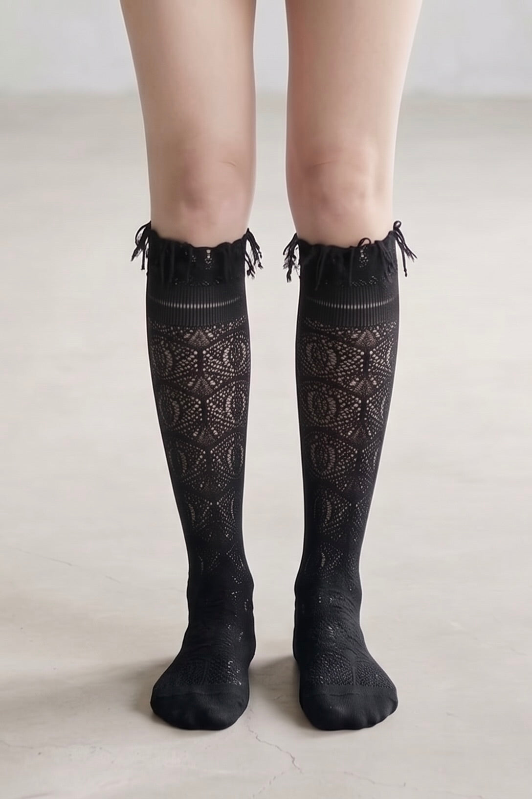 Wine sheer jacquard lace knee-high socks with intricate openwork pattern and tassel trim styled with black pointed heels.